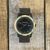 Inverness SS watch featuring multi-colored bamboo bezel, black dial, and stainless steel strap on a wooden background.