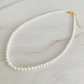 Graduated cream-toned pearl necklace with gold clasp, sizes 4mm to 7mm, ideal for layering or as a statement piece.