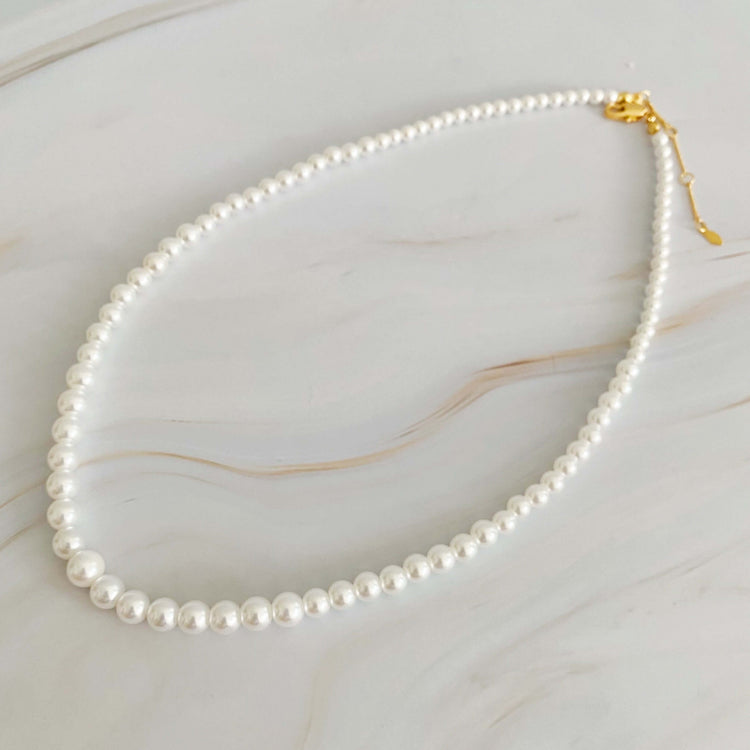 Graduated cream-toned pearl necklace with gold clasp, sizes 4mm to 7mm, ideal for layering or as a statement piece.