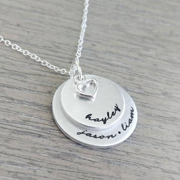 Personalized sterling silver necklace featuring two engraved discs and a heart charm, ideal gift for loved ones.