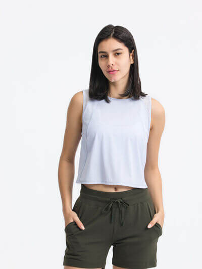 Model wearing Millennia Round Neck Cropped Active Tank in light blue with olive green shorts, showcasing activewear style.