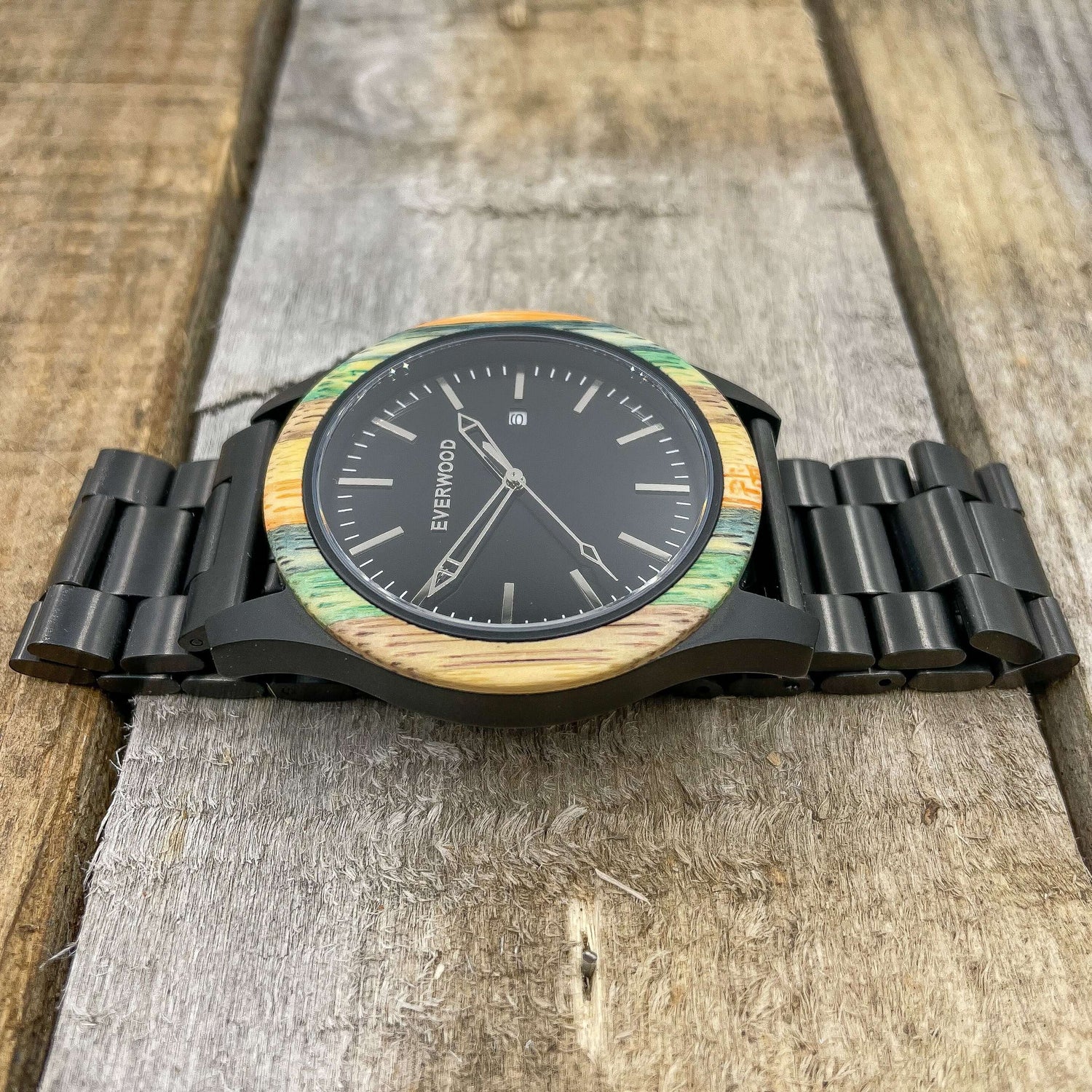 Inverness SS watch featuring multi-colored bamboo bezel and stainless steel adjustable strap on wooden surface.