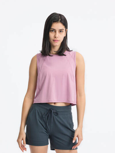 Millennia round neck cropped active tank in lightweight pink with sleeveless design, paired with dark shorts.