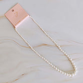 Elegant graduated pearl necklace on display with a tag, showcasing glass pearls and an 18k gold-plated clasp.