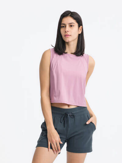 Model wearing a pink Millennia Round Neck Cropped Active Tank paired with dark shorts, showcasing a stylish and comfortable activewear look.