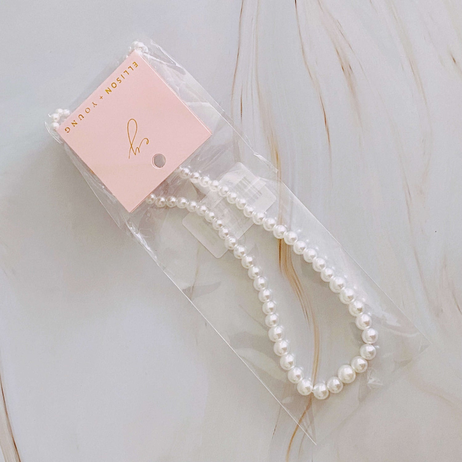 Graduated cream pearl necklace in packaging, showcasing elegant design and 18k gold-plated detail.