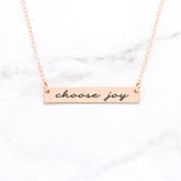 Choose Joy rose gold quote bar necklace with inspirational message on a marble background.