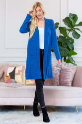 Model wearing a blue brushed sweater pocket cardigan over a white top and black pants, styled for cold weather.