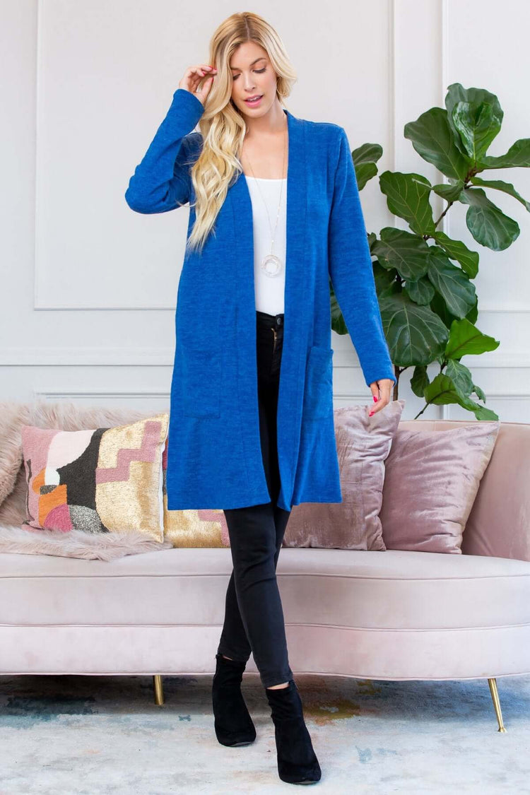 Model wearing a blue brushed sweater pocket cardigan over a white top and black pants, styled for cold weather.