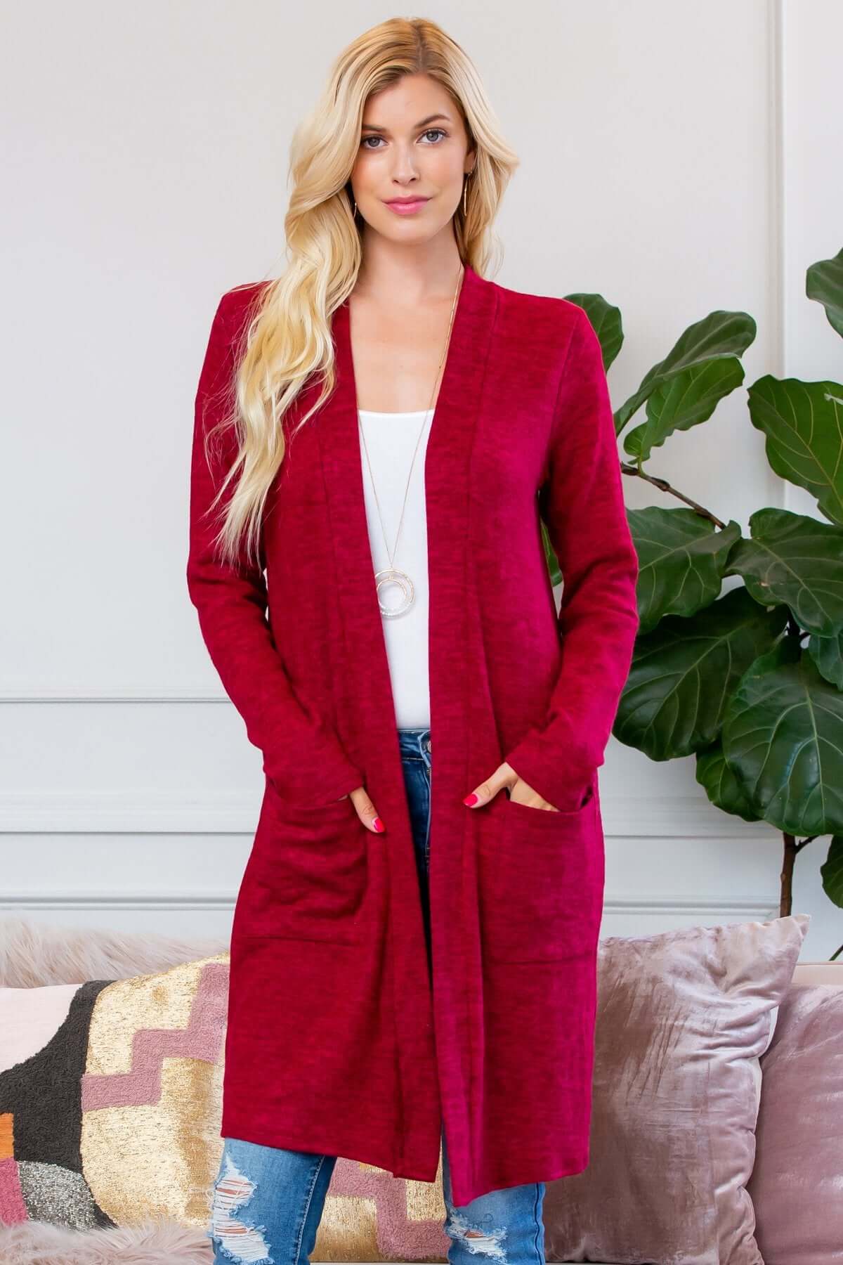 Woman wearing a soft brushed sweater pocket cardigan in burgundy, styled with jeans and a white top, showcasing long sleeves and pockets.