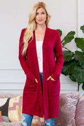 Woman wearing a soft brushed sweater pocket cardigan in burgundy, styled with jeans and a white top, showcasing long sleeves and pockets.