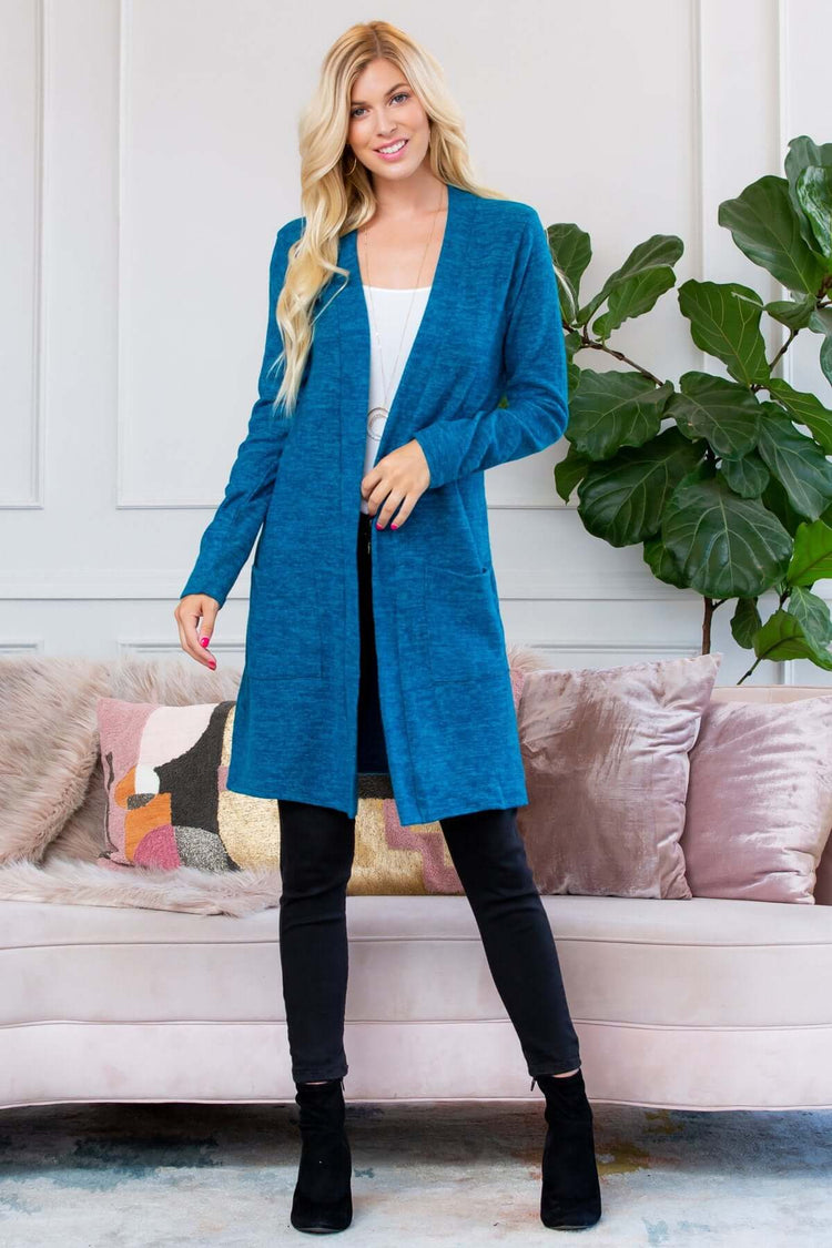 Model wearing a brushed sweater pocket cardigan in teal, styled with black leggings and ankle boots.