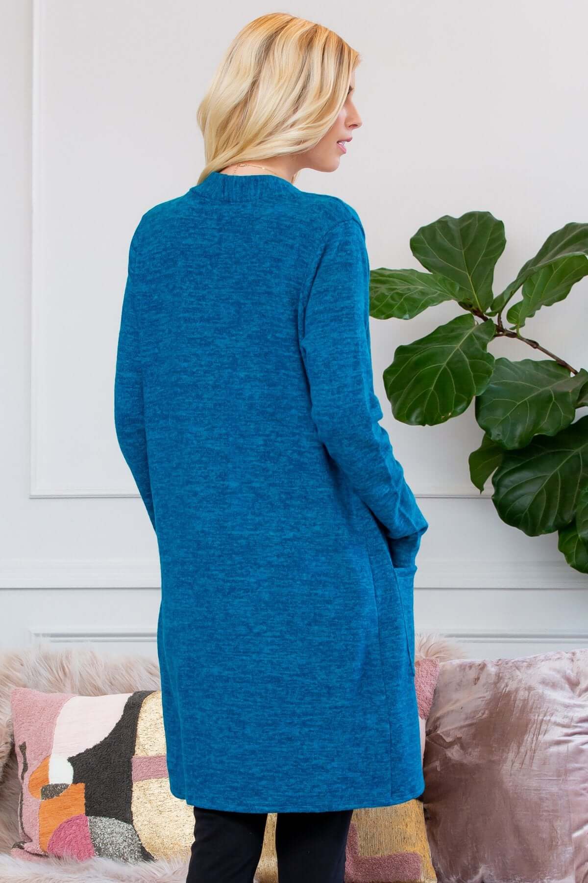 Model wearing a blue brushed sweater pocket cardigan, showcasing its long silhouette and styling options.