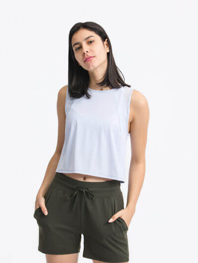 Model wearing a light blue cropped active tank and dark shorts, showcasing a sporty and stylish look for workouts.
