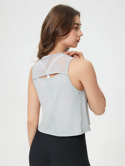 Model wearing a Millennia round neck cropped active tank, showcasing its stylish back design and lightweight fabric.