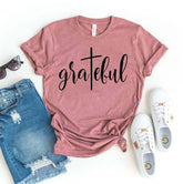 Grateful T-Shirt in mauve, featuring soft flex print, paired with denim shorts and white shoes on a flat surface.