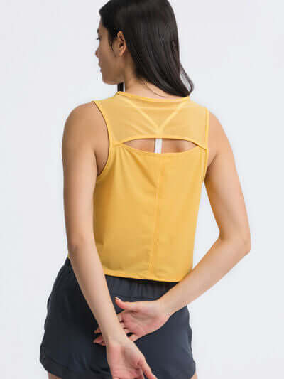 Rear view of a woman wearing a yellow cropped active tank with open back design, showcasing comfort and style.