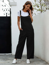 Stylish woman in black woven retro casual long overalls with slant pockets and a square collar, paired with a white tee.