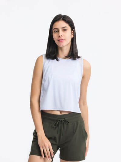 Model wearing Millennia round neck cropped active tank in light grey with olive green shorts, showcasing a casual active style.