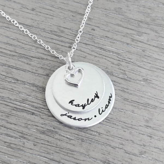 Personalized sterling silver necklace with two discs and heart charm, featuring names hand-stamped on the pendants.