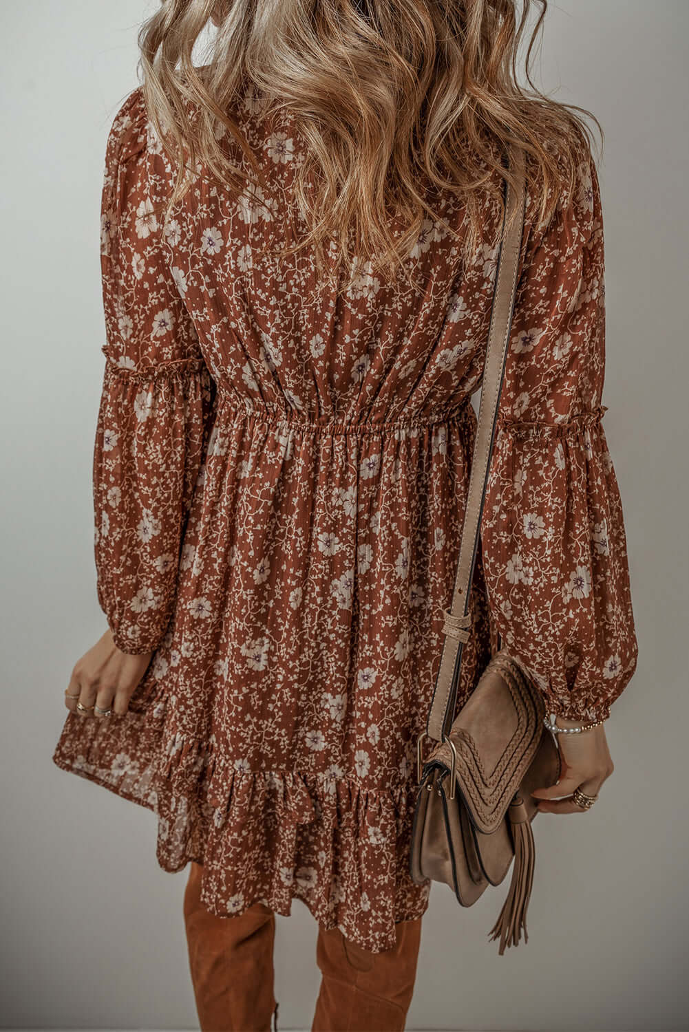 Ashley Boho Floral Puff Sleeve Mini Dress in rust with ruffled hem and long sleeves, styled with a crossbody bag.