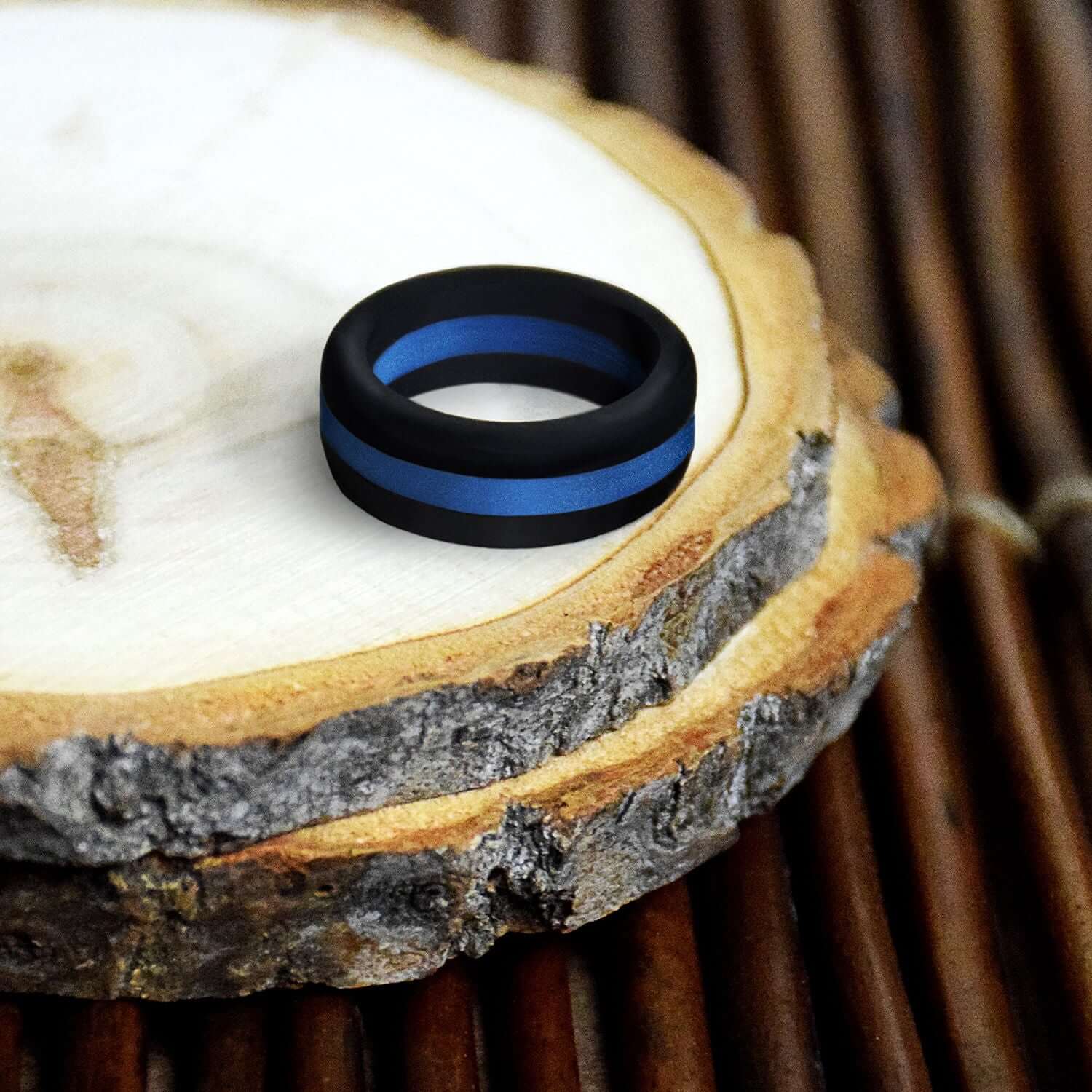 Durable black and blue stripe silicone ring on natural wood surface, perfect for active lifestyles and adventures.