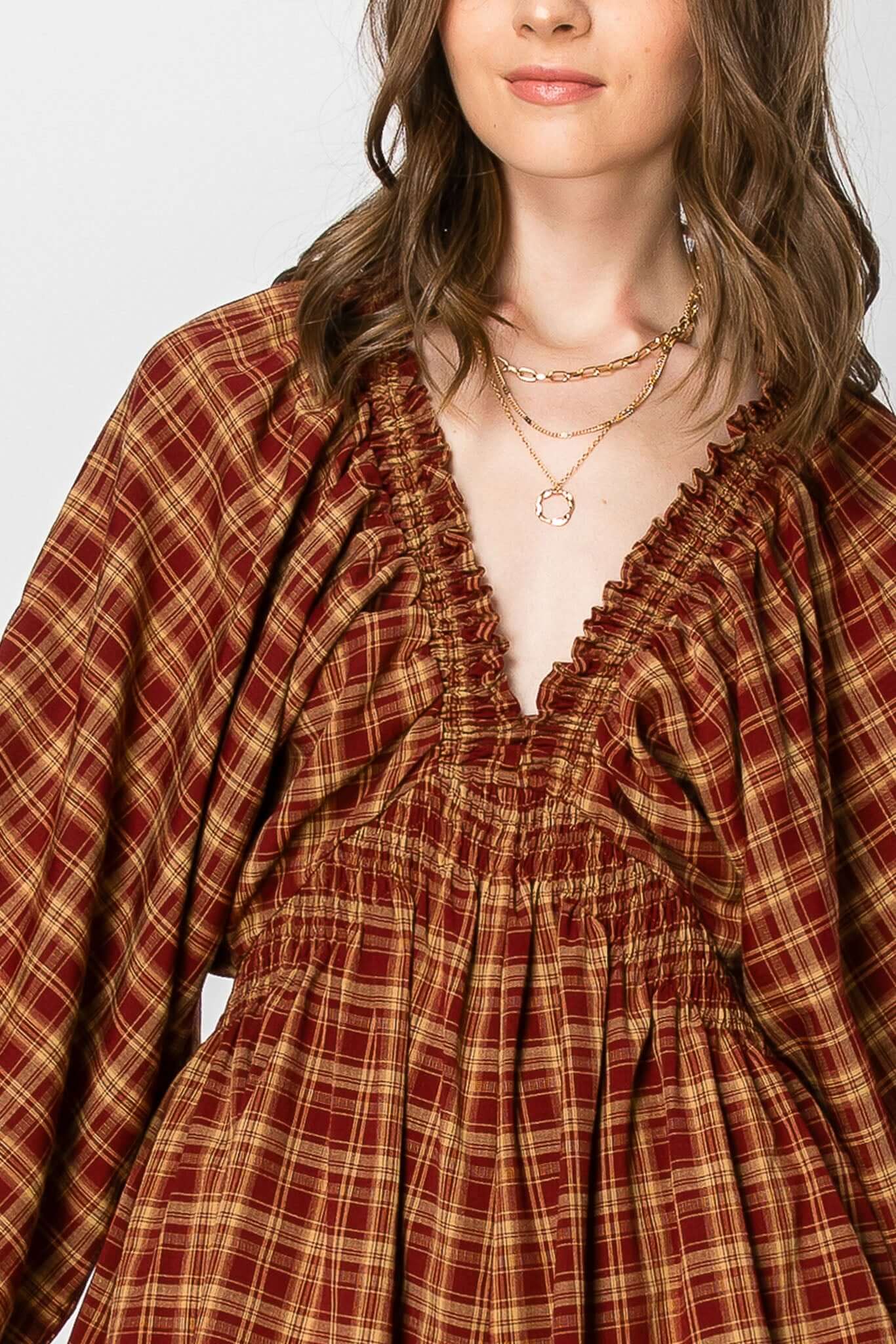 Dolman sleeve plaid smocked deep V-neck romper with pockets, featuring balloon sleeves and autumn vibe.