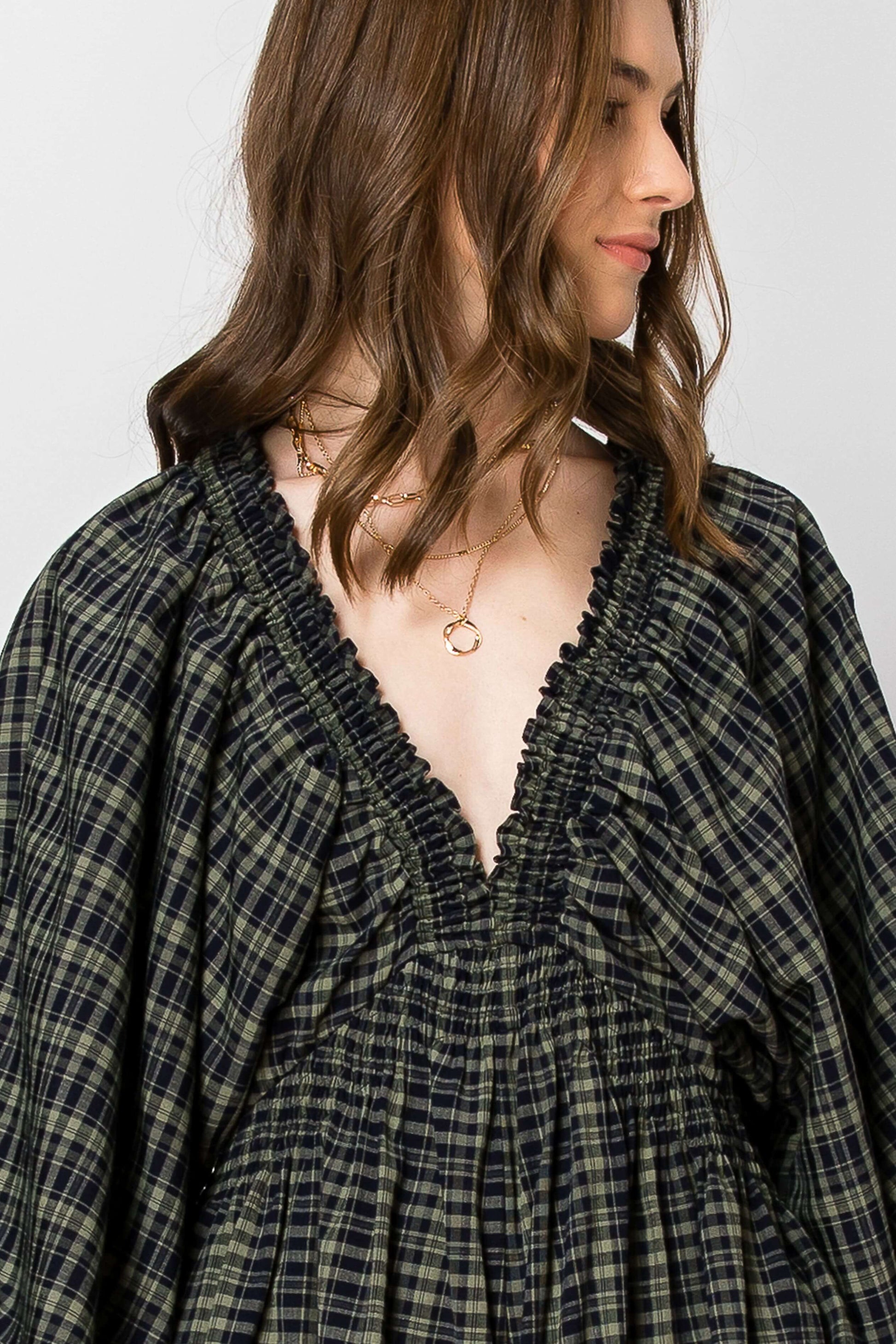 Dolman sleeve plaid smocked deep V-neck romper with pockets, showcasing fall vibes in a comfy, oversized design.