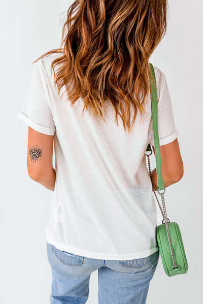 Back view of a woman wearing a white 'Not Lucky Just Blessed' round neck T-shirt with a green shoulder bag.