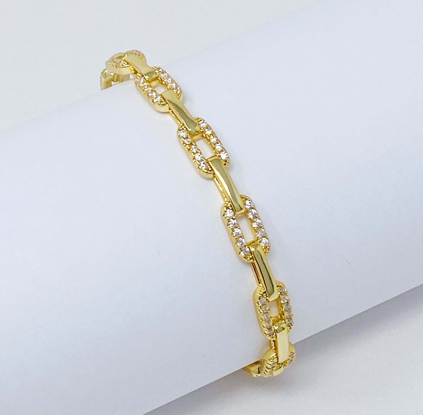 Alternatively linked open bangle bracelet in 18k gold plating with cubic zirconia, adjustable for comfort and style.