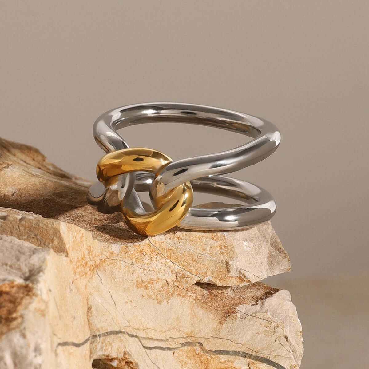 18K gold-plated hollow ring with unique gold and silver design on a rock background.