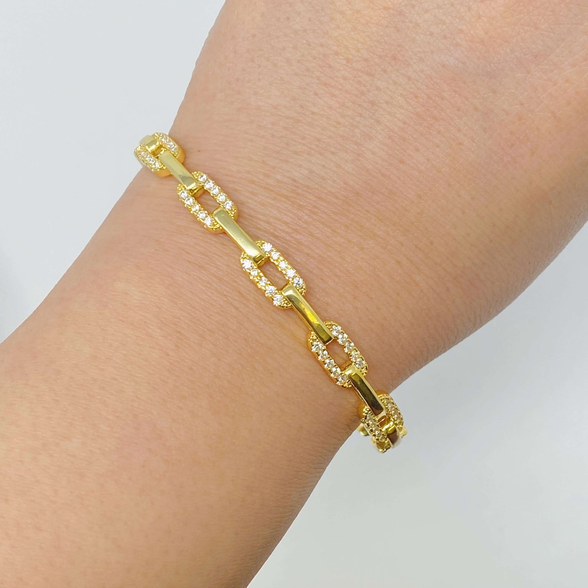 Stylish alternatively linked open bangle bracelet in 18k gold plated brass with cubic zirconia on a wrist.