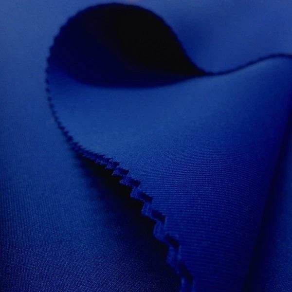 Close-up of rich blue neoprene fabric with a smooth texture and visible stitching detail.