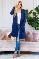 Model wearing a navy brushed sweater pocket cardigan with a long silhouette and side pockets, styled with jeans.