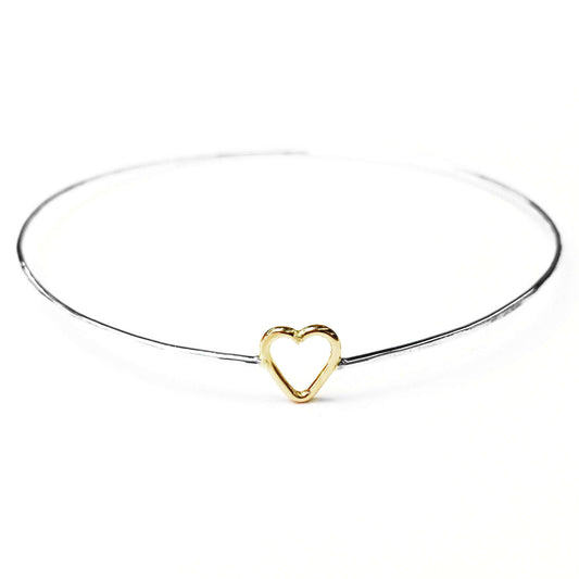 Junibel Sweetheart Bangle featuring a delicate gold heart charm on a sleek silver band, perfect for modern elegance.