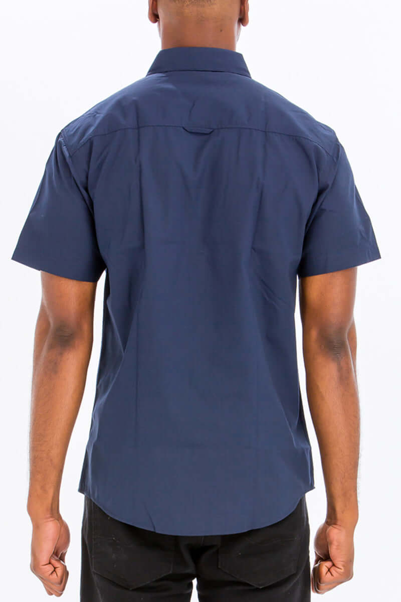 Back view of a navy short sleeve two pocket button down shirt made of 80% cotton and 20% polyester.