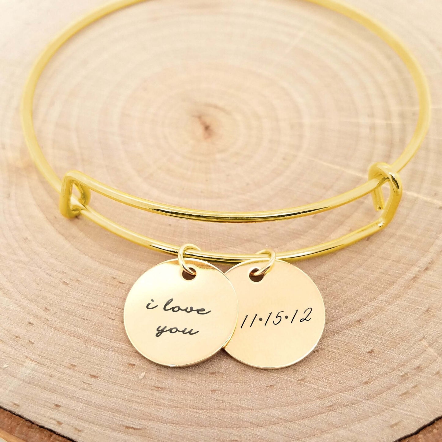 Personalized gold bangle bracelet with engraved discs saying 'I love you' and '11/15/12', perfect anniversary gift.