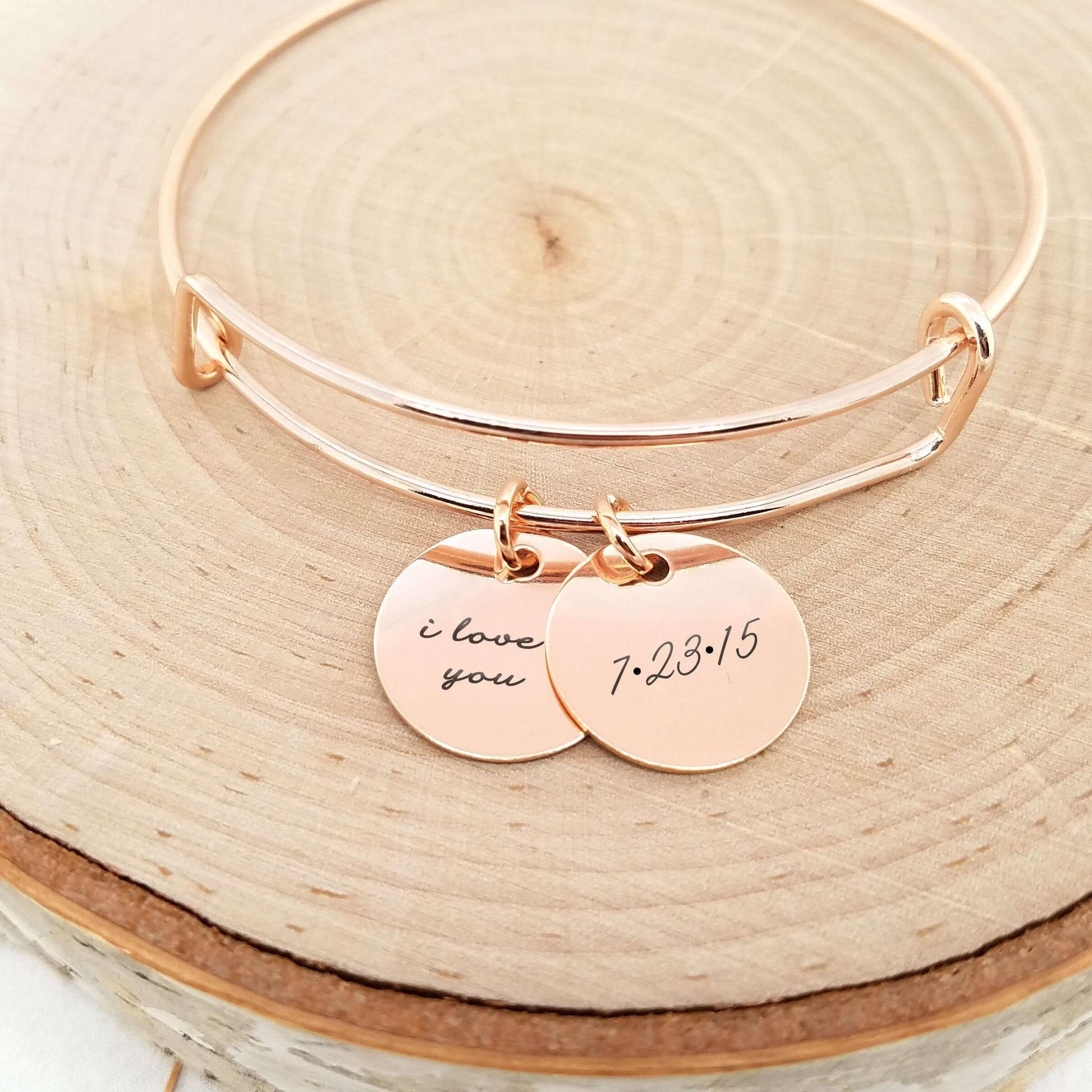 Personalized anniversary bracelet featuring engraved discs 'I love you' and '7:23:15' in rose gold.