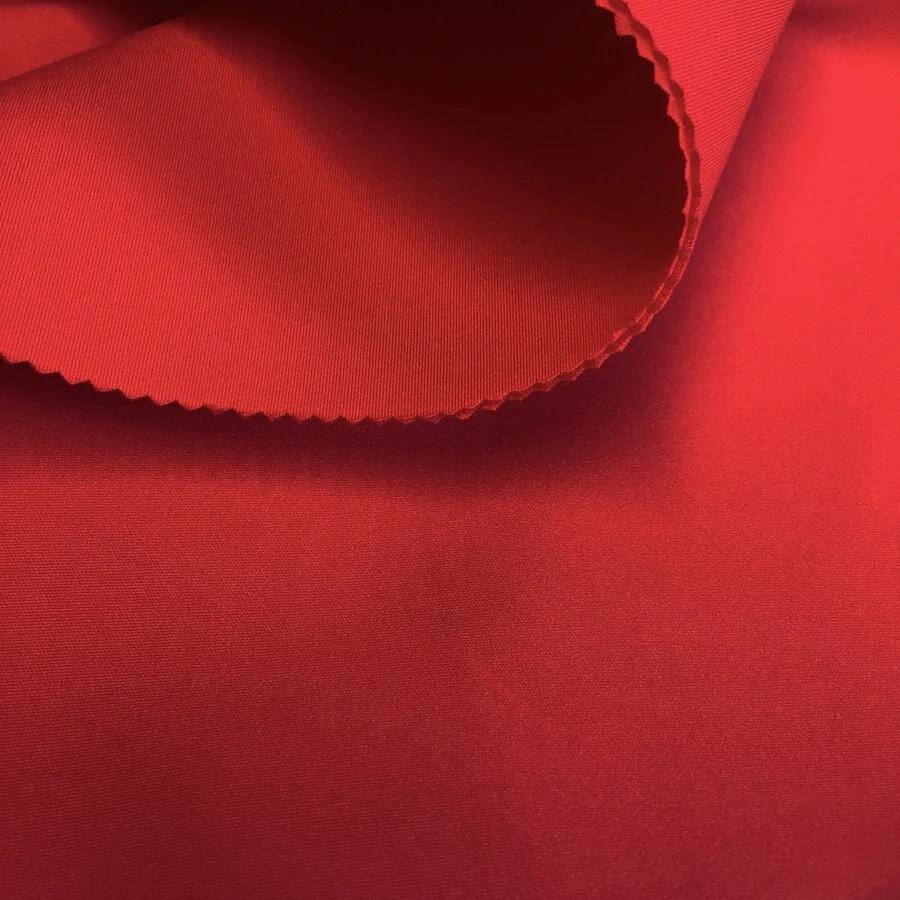 Close-up of vibrant red neoprene fabric showcasing smooth texture and scalloped edge.