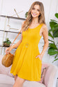 Yellow racerback tank dress with on-seam pockets, styled with a round pendant and woven bag.