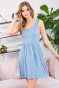 Woman modeling a light blue racerback tank dress with flared silhouette and crew neckline, styled with a necklace.