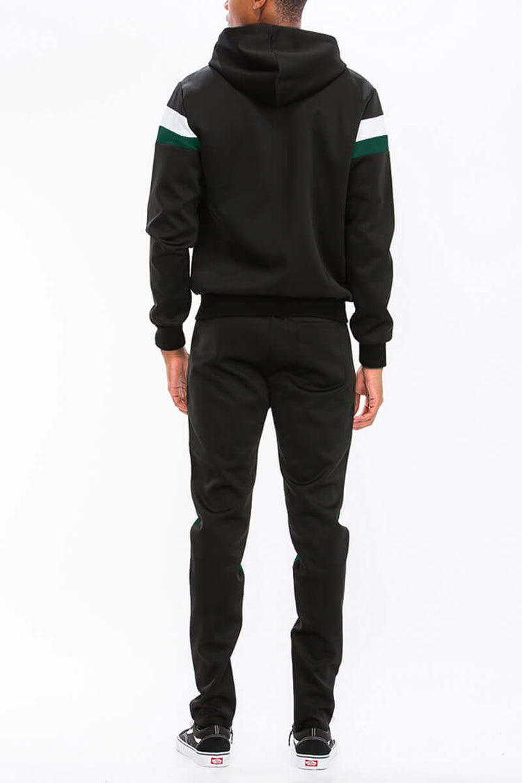 Back view of a man in a chevron stripe color block full zip track suit with a hoodie and ankle zipper pants.