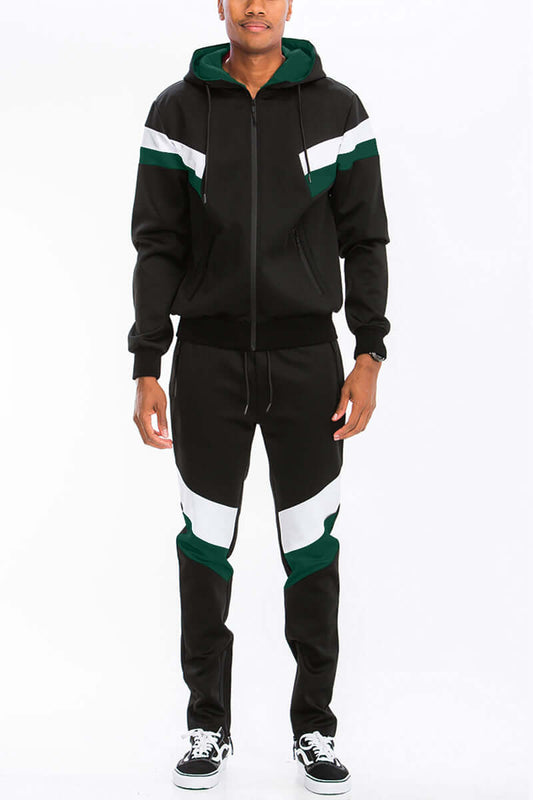 Man wearing chevron stripe color block track suit with full zip hoodie and ankle zipper track pants in black and green.