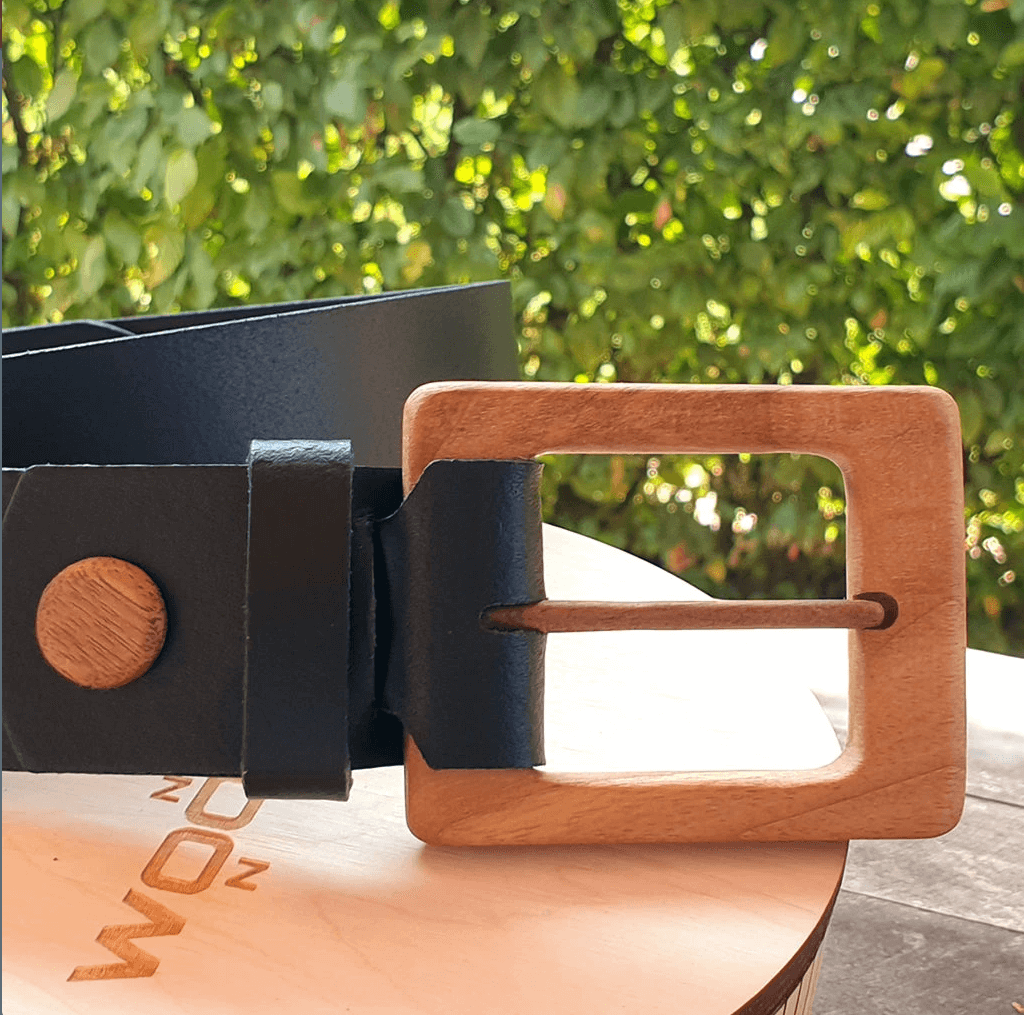 Luxury men's leather belt with natural walnut buckle on wooden background, showcasing minimalistic design.