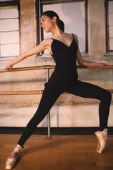 Dancer in a black jumpsuit showcasing elegance and movement in a ballet studio.