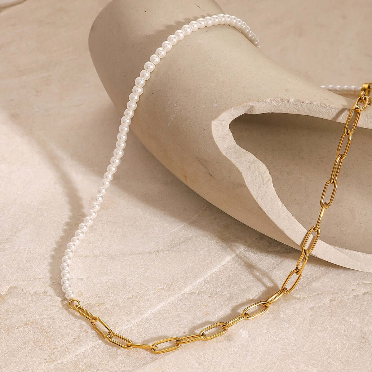 18K gold plated necklace featuring a unique pearl beaded design, elegantly displayed on a sculptural surface.