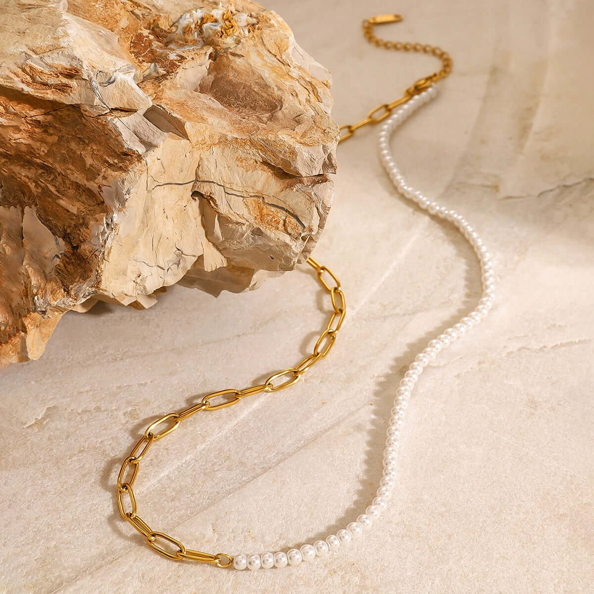 18K gold plated chain and pearl beaded design necklace on a rocky surface, highlighting modern elegance.