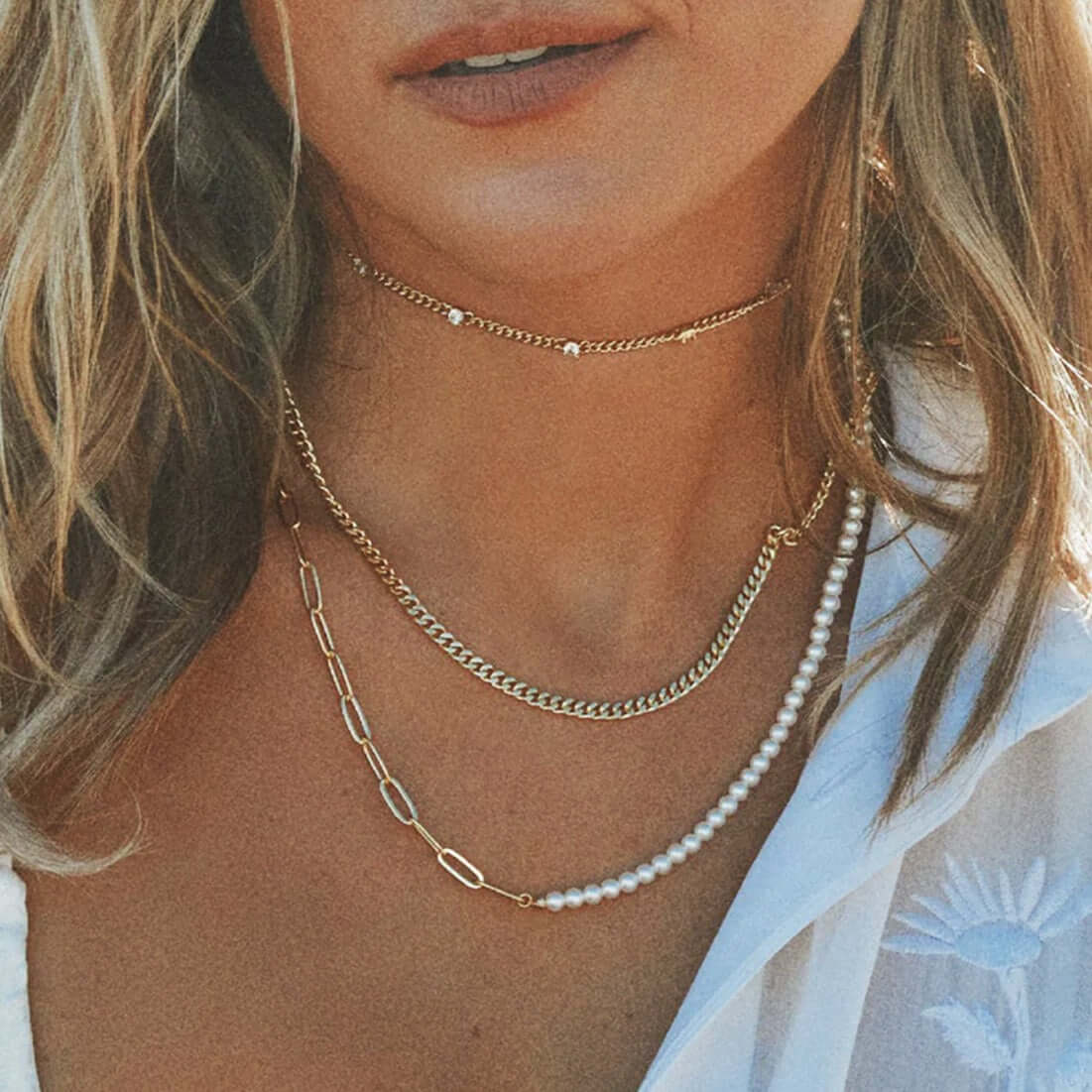 Close-up of a woman wearing layered 18K gold plated necklace with pearl beads, showcasing modern and classic elegance.