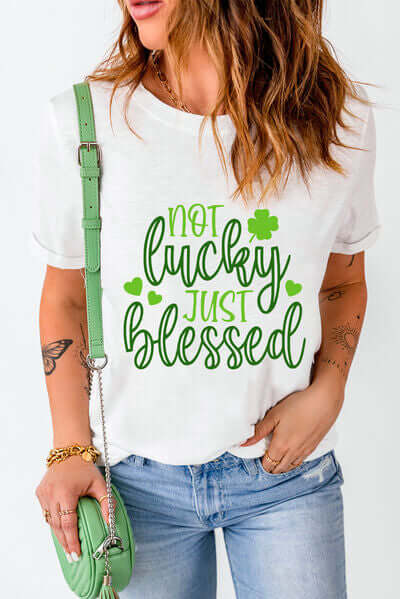 Woman wearing 'Not Lucky Just Blessed' round neck t-shirt with green lettering and a stylish crossbody bag.