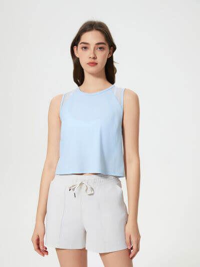 Model wearing a blue cropped active tank top with white shorts, showcasing a stylish and comfortable workout look.